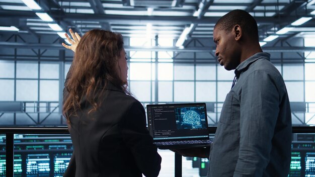 IT expert coding on notebook in server room using artificial intelligence