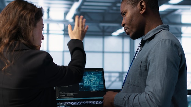 IT expert coding on notebook in server room using artificial intelligence
