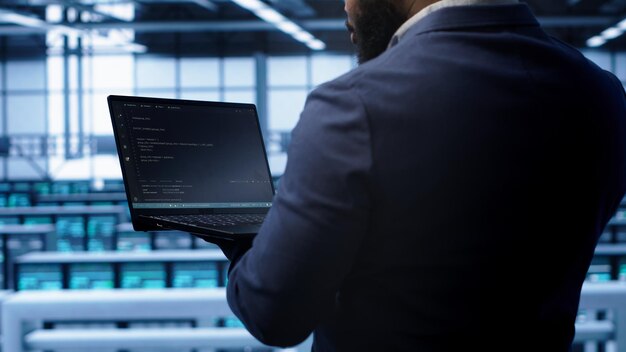 Programmer in data center doing yearly maintenance checkup using laptop