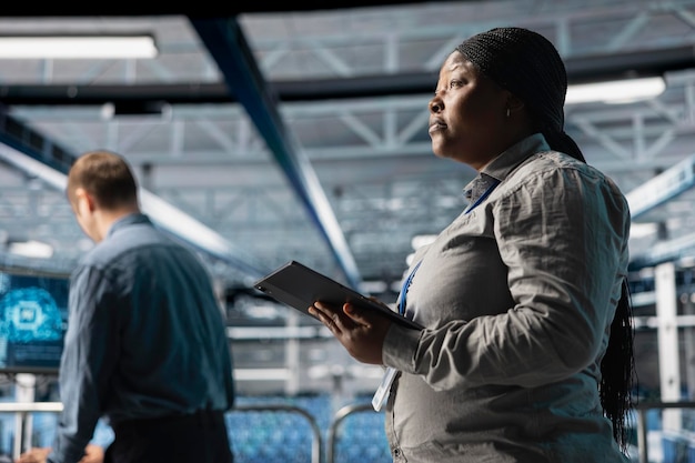 Server room infrastructure engineers scripting automated workflows using software on tablet