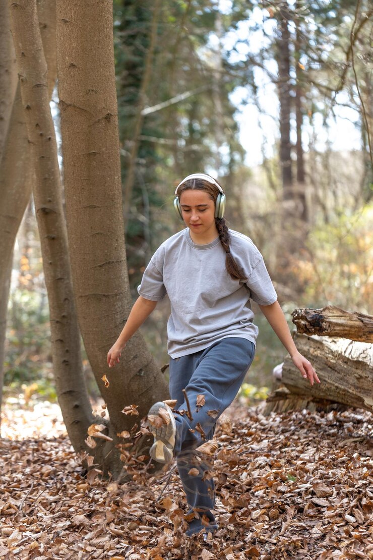Ilmainen Kuva teenage girl walking in the forest girl listening to music with headphones in the forest