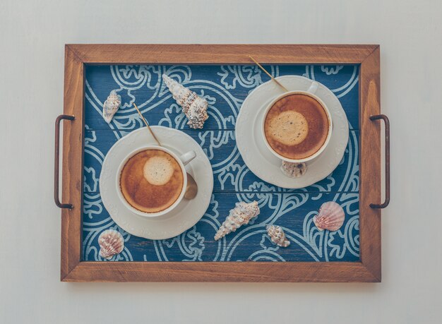 2 tasses de café dans le plateau de service avec des objets décoratifs vue de dessus sur blanc