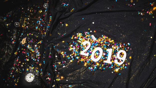 2019 figures lumineuses entre des confettis sur un drap noir