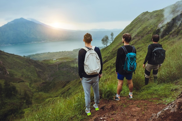 3 randonneurs homme regardant le lever du soleil sur le concept de liberté de la montagne Ascension vers l'équipement de guide de voyage volcan