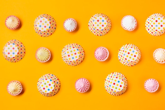 Photo gratuite aalaw avec des gâteaux de papier à pois forme dans une rangée sur fond jaune