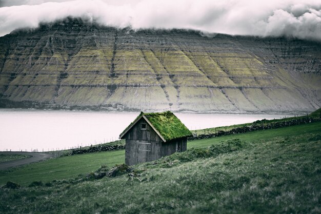 Abri en bois brun avec de l'herbe sur le toit sur les falaises rocheuses