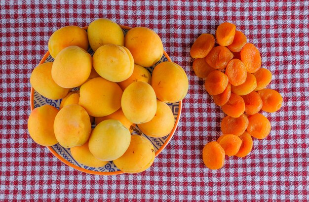 Abricots aux abricots secs dans une assiette sur une toile de pique-nique, à plat.