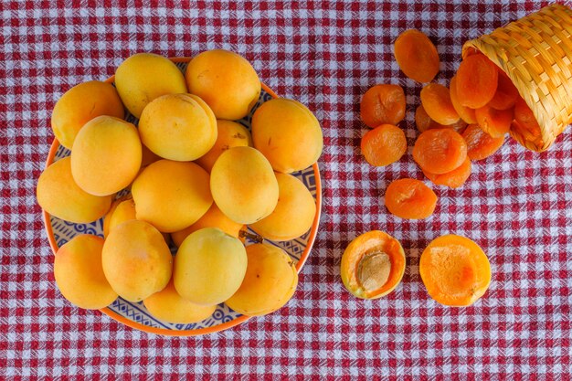 Abricots dans une assiette avec des abricots secs à plat poser sur un chiffon de pique-nique