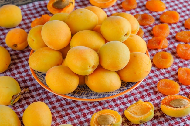 Abricots dans une assiette avec abricots secs vue de dessus sur un chiffon de pique-nique