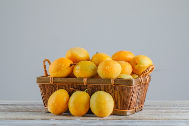 Abricots dans un panier sur table en bois. vue de côté.