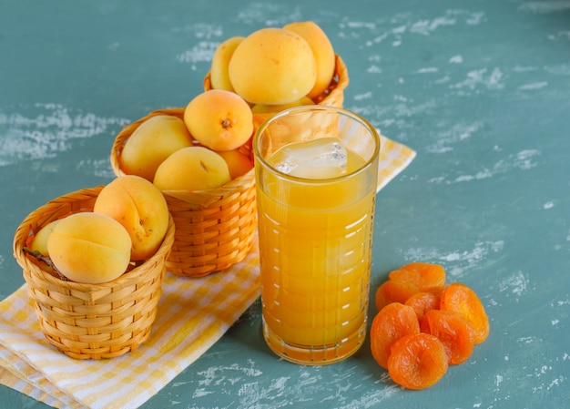 Abricots dans des paniers avec abricots secs, vue de dessus de jus sur plâtre et tissu de pique-nique