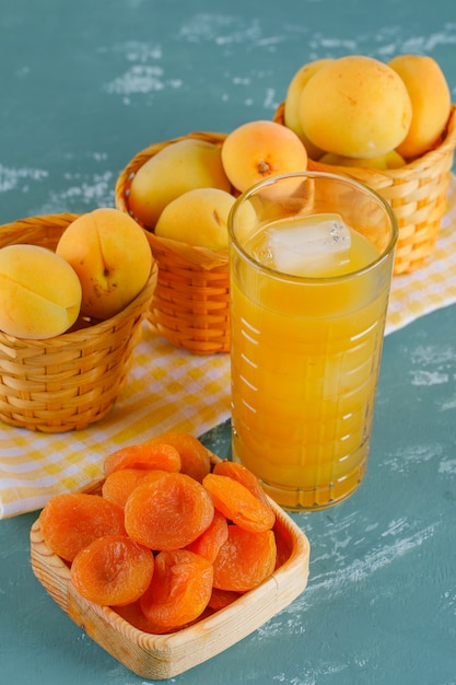 Abricots dans des paniers avec abricots secs, vue de dessus de jus sur plâtre et tissu de pique-nique