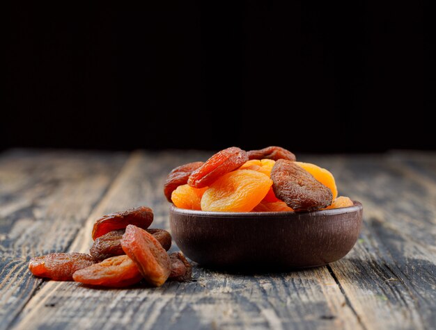 Abricots secs dans un bol d'argile sur table en bois