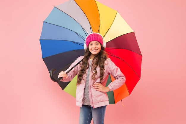 Accessoire en cas de pluie. un petit enfant apprécie la musique sous un accessoire de pluie parapluie coloré. petite fille en manteau avec accessoire de mode pour la saison d'automne des pluies. l'accessoire parfait pour la garder au sec.
