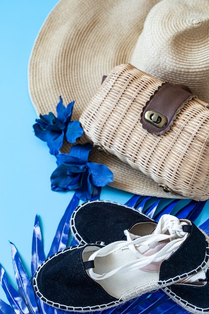 Accessoires d'été, chaussures et chapeau avec sac sur fond bleu.