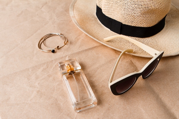 Accessoires lunettes de soleil parfum et chapeau sur la surface de l'artisanat