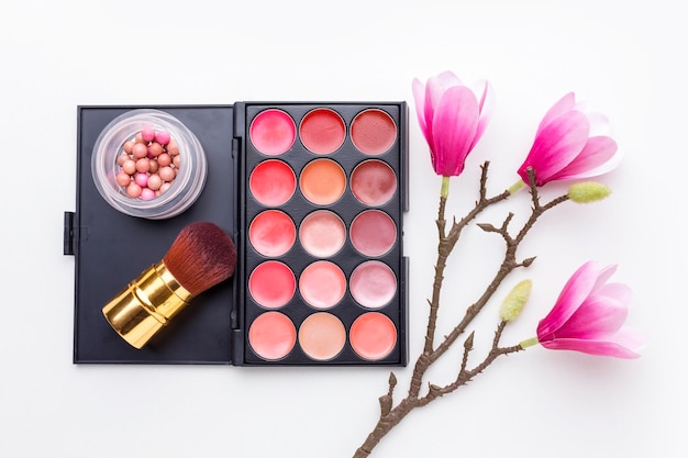 Accessoires de maquillage vue de dessus avec des fleurs