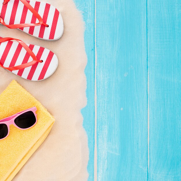 Accessoires de plage sur la planche bleue et le sable - fond de vacances d&#39;été