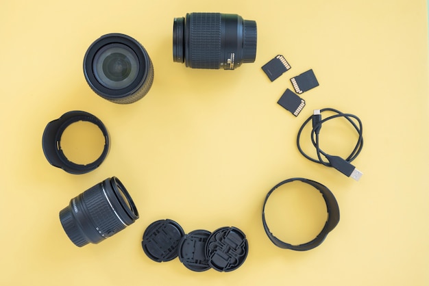 Accessoires pour appareils photo numériques professionnels disposés en cercle sur fond jaune