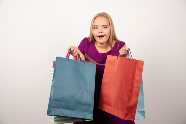Accro du shopping blonde tenant des sacs à provisions colorés.