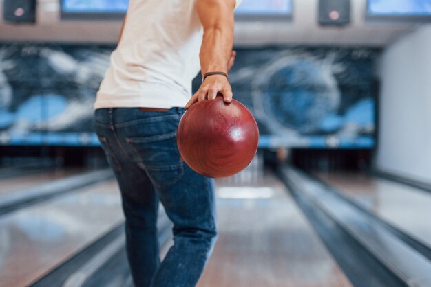 Activités du week-end. Vue de particules arrière de l'homme en vêtements décontractés jouant au bowling dans le club