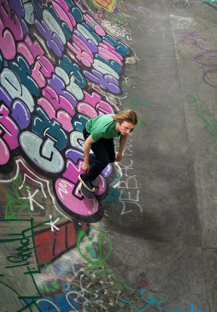 Adolescent à angle élevé faisant des tours sur une planche à roulettes