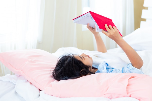 Adolescent asiatique femme lire un livre de journal sur le lit