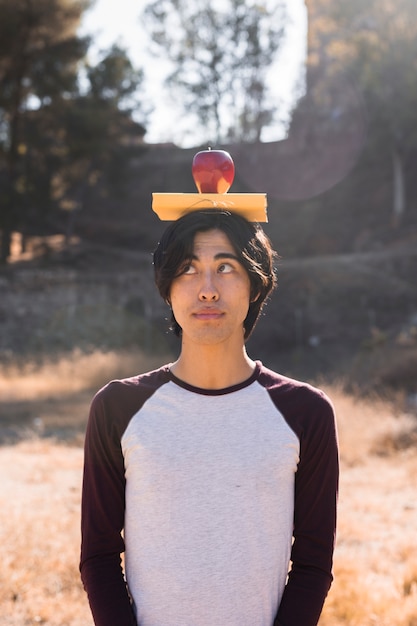 Photo gratuite adolescent asiatique avec livre et pomme sur la tête