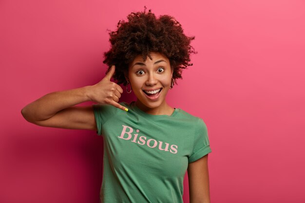 Adolescent aux cheveux bouclés positif me fait téléphoner près de l'oreille