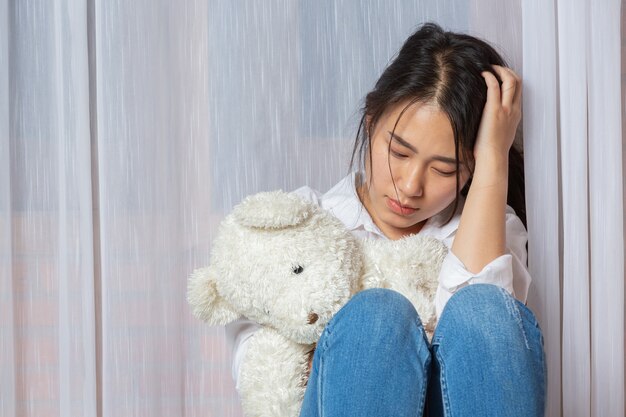 Adolescent brune triste tenant un ours en peluche à la maison