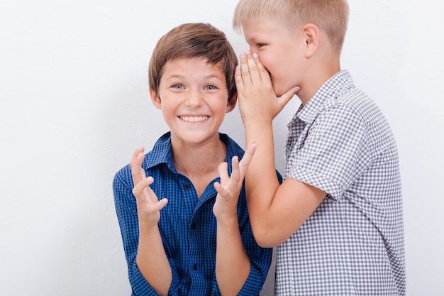 Adolescent chuchotant un secret à l'oreille d'un ami surpris sur fond blanc