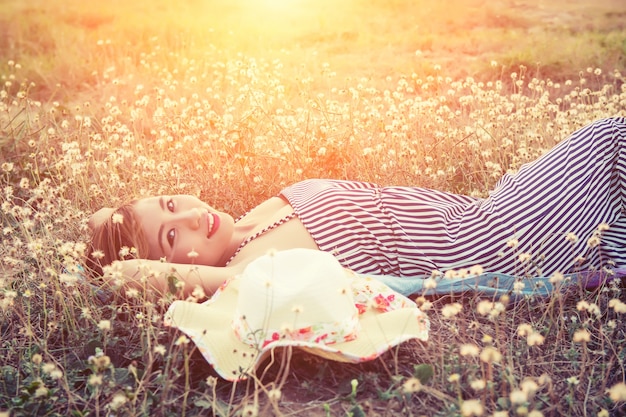 Adolescent couché sur le pré au coucher du soleil