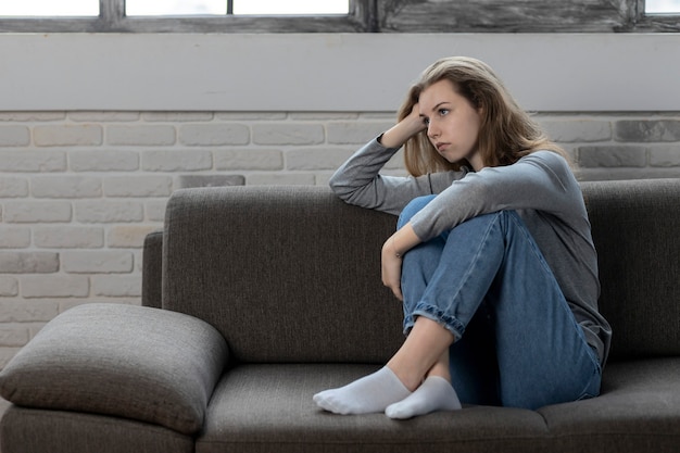 Adolescent déprimé avec des émotions et des sentiments tristes assis sur le canapé à la maison
