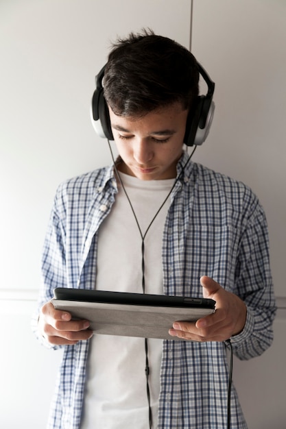 Adolescent en écoutant de la musique et en parcourant la tablette