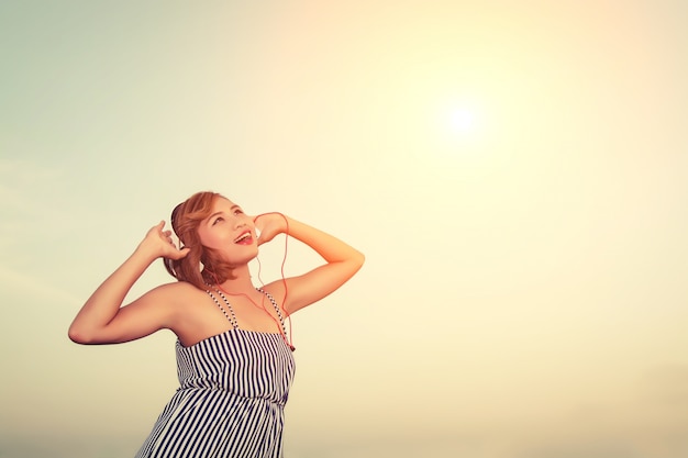 Photo gratuite adolescent écouter de la musique avec fond de ciel