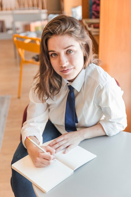 Adolescent, écrivant dans le cahier et regardant la caméra