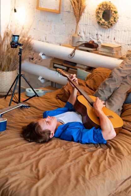 Photo gratuite adolescent enregistrant de la musique avec sa guitare dans son home studio