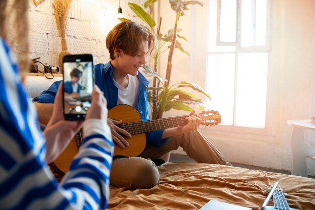 Adolescent et fille enregistrant de la musique avec une guitare dans leur home studio