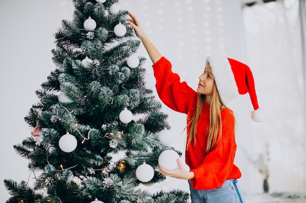 Adolescent fille mignonne en bonnet de Noel rouge par arbre de Noël