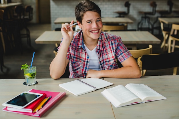 Photo gratuite adolescent heureux posant avec le matériel scolaire