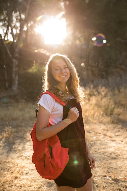Photo gratuite adolescent heureux avec sac à dos en souriant dans la campagne