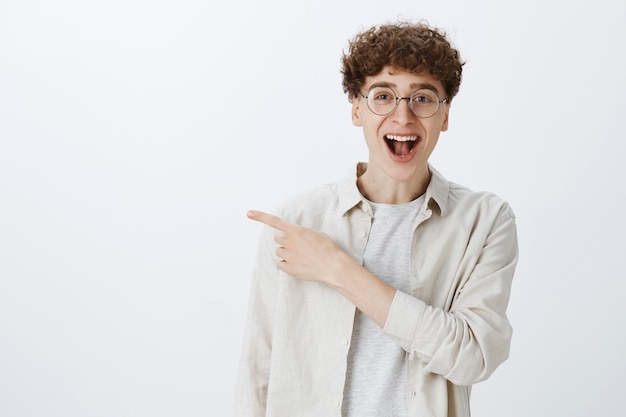 Adolescent impressionné et surpris posant contre le mur blanc