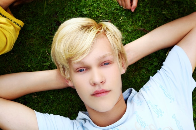 Adolescent jeune et attrayant se reposer dans l'herbe