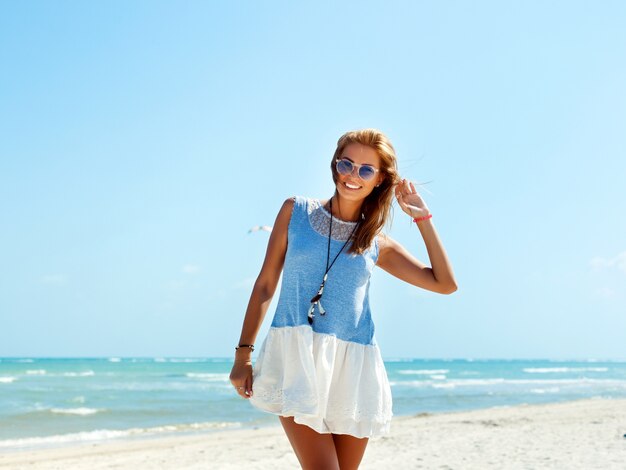 Adolescent avec des lunettes de soleil et robe bleue sur la plage