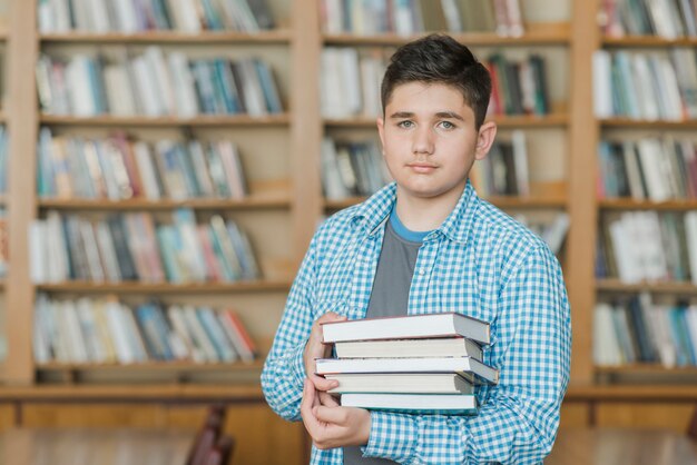 Adolescent masculin avec une pile de livres