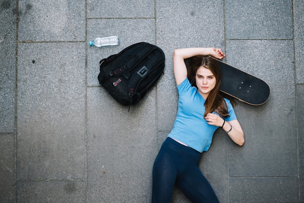 Photo gratuite adolescent posant avec la tête sur la planche à roulettes