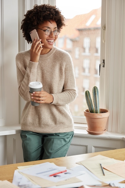 Photo gratuite adolescent positif avec son téléphone posant à la maison