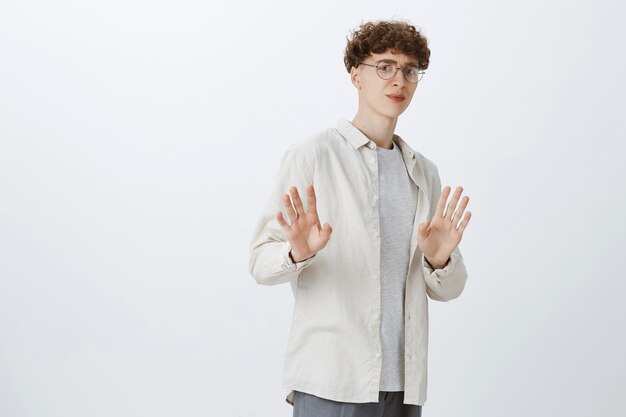 Adolescent réticent posant contre le mur blanc