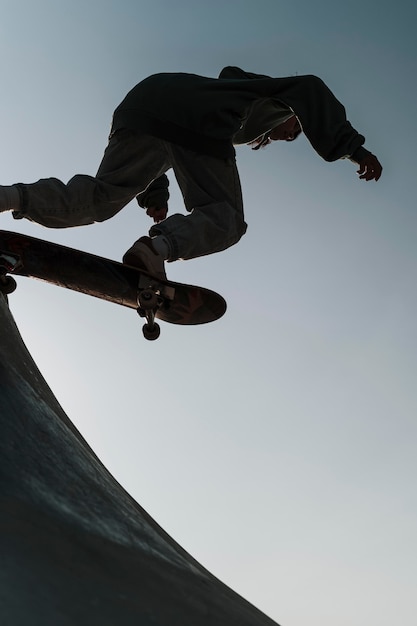 Adolescent s'amusant avec planche à roulettes dans le parc à l'extérieur