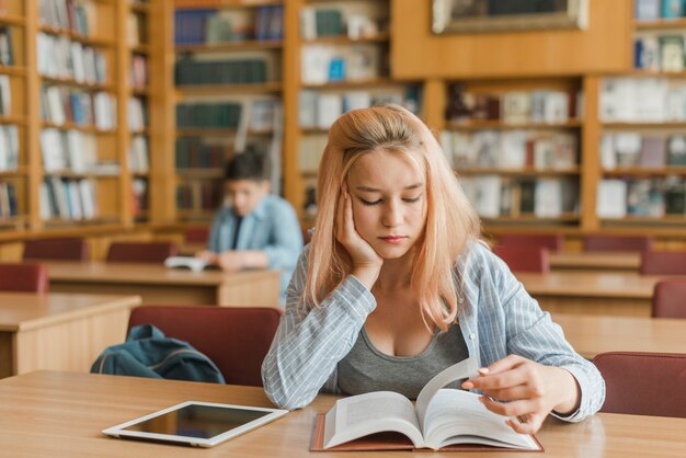 Adolescent s&#39;ennuie étudier dans la bibliothèque